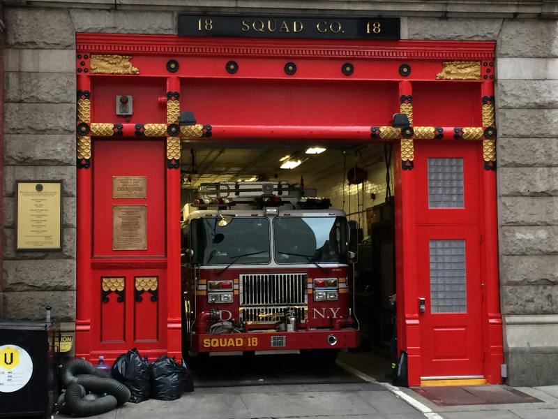 Bright red entrance to a NYC firehouse. The fire engine is backed in and ready to roll.