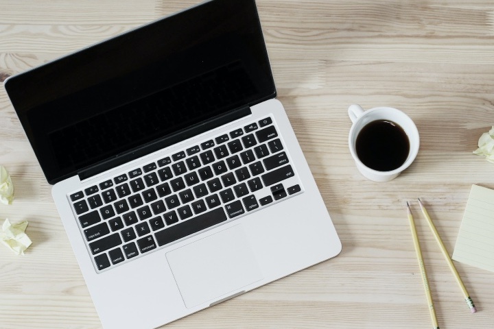 Laptop open on a desk, ready to work with a cup of coffee.